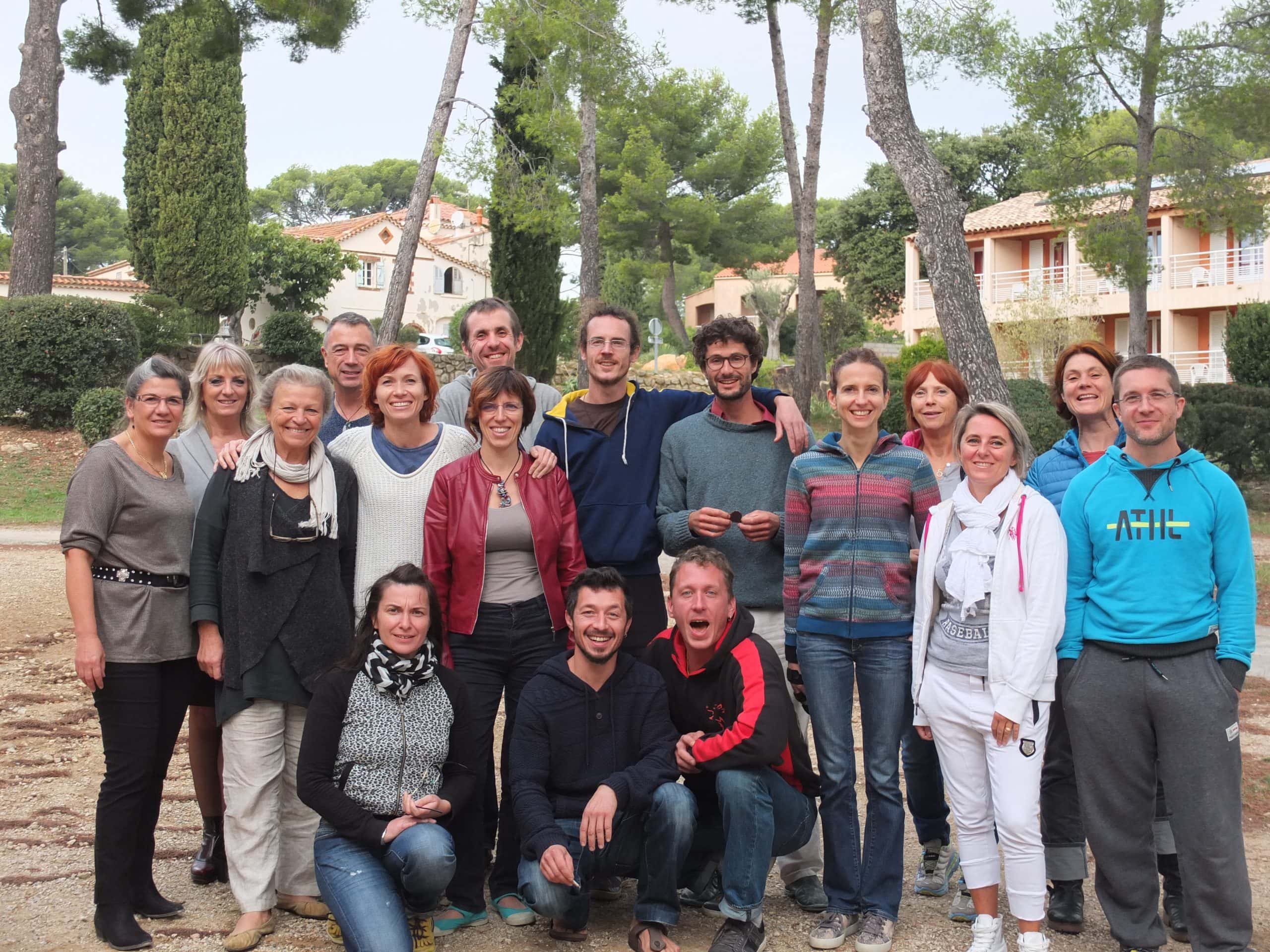Photo de groupe d’une promotion du CoTM en extérieur, devant les bâtiments et les pins.