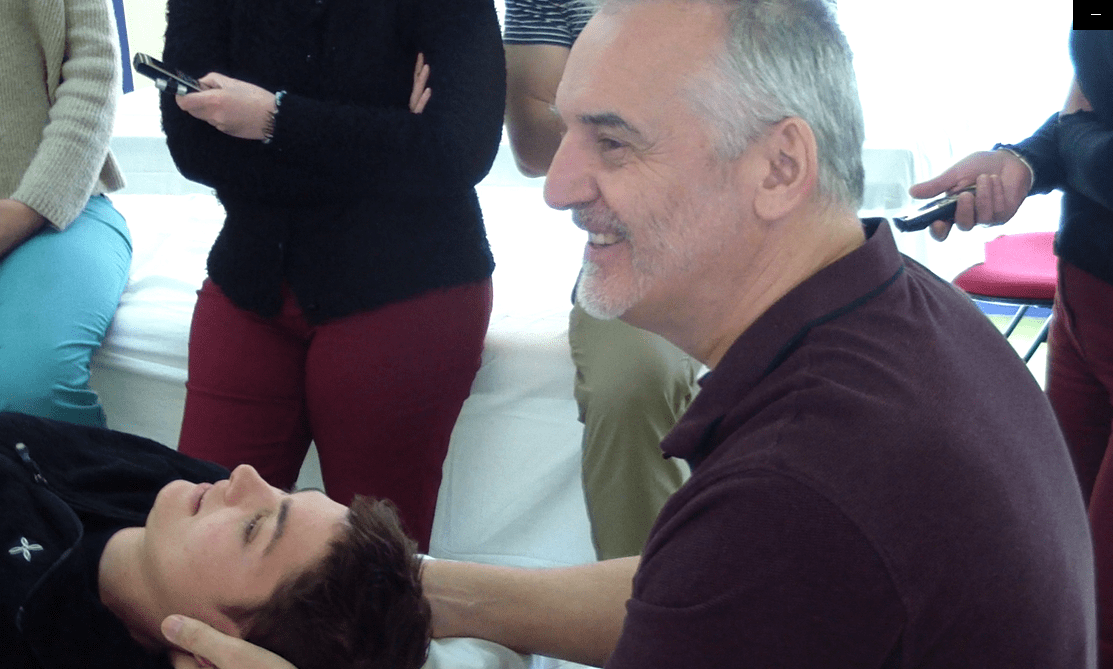 Bernard Rochas, souriant, en train de travailler sur un patient pendant un séminaire.
