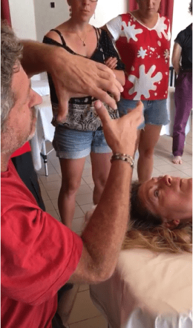 Guillaume O’Byrne en démonstration, les mains au visage d’une personne allongée, entouré d’étudiants.